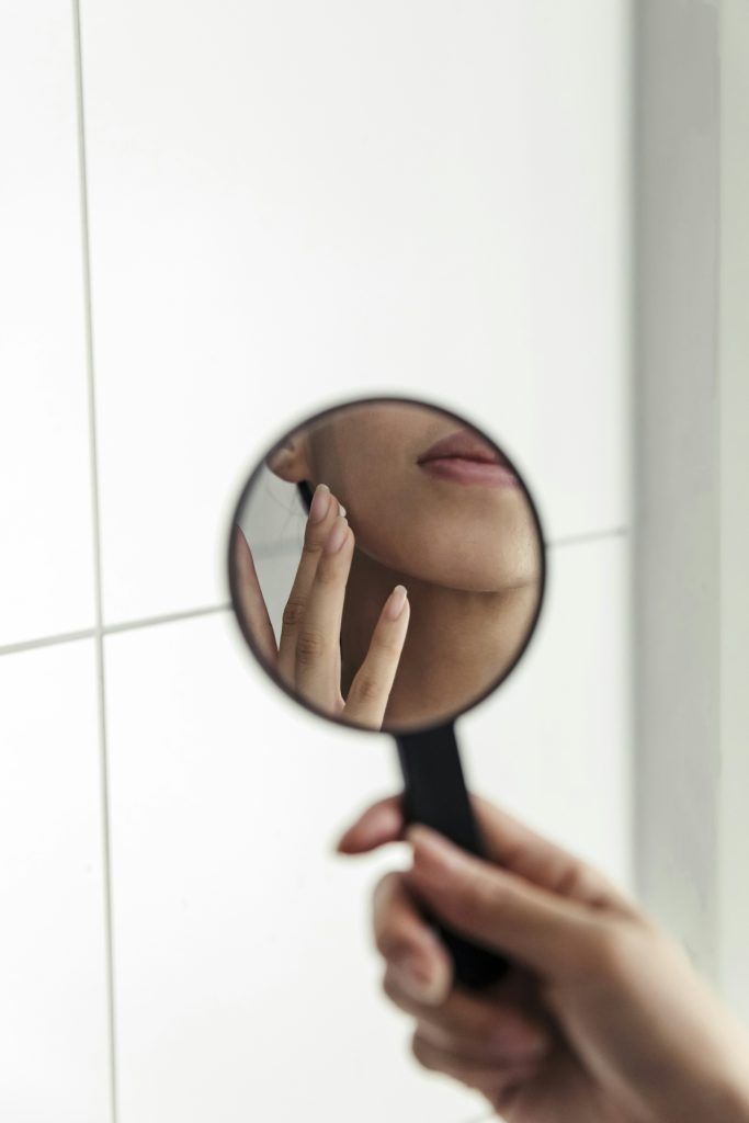 women looking into mirror inspecting her own skin