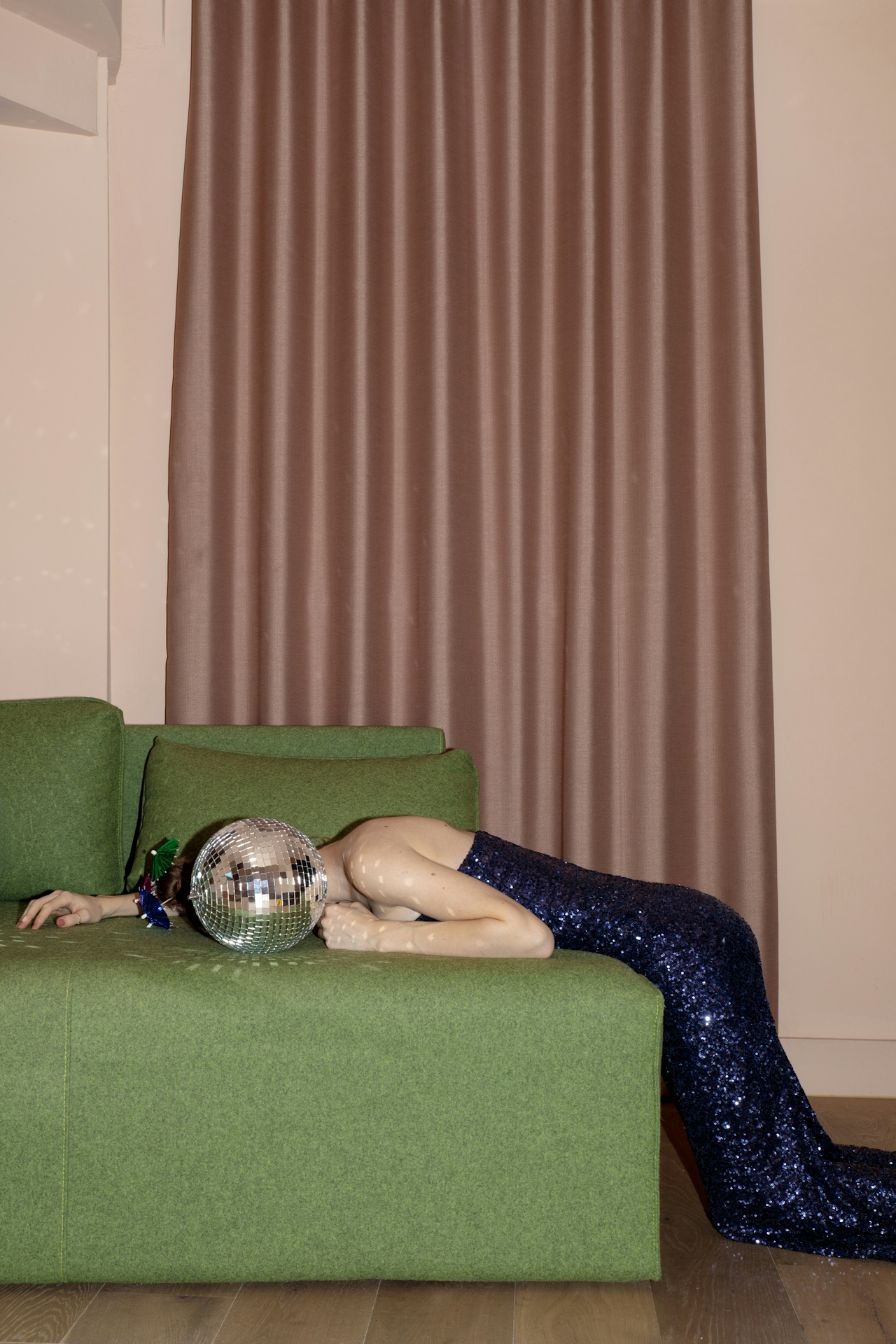 woman tired after a party, disco ball on green sofa